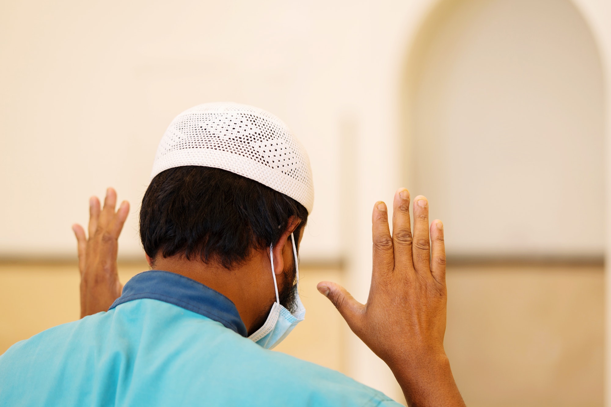 View from behind Muslim man praying in the mosque